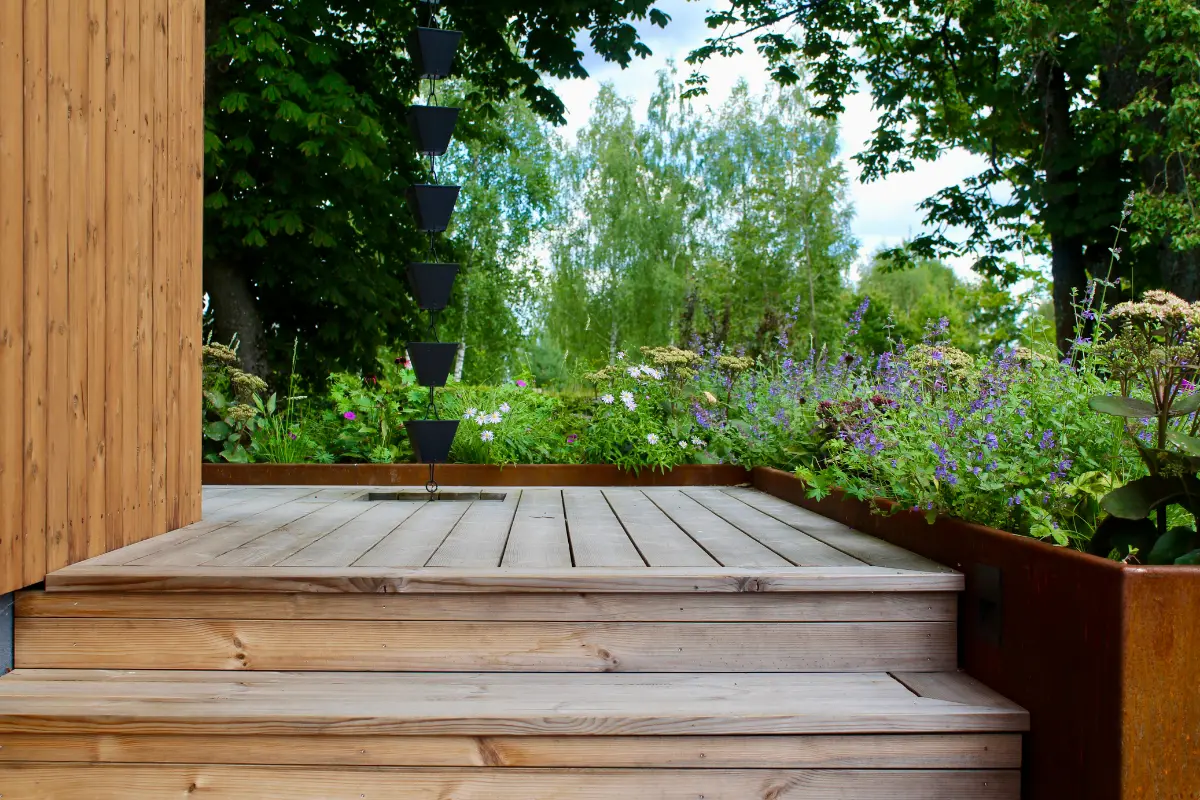 Termo medienos lauko dailylentės ir terasa su laiptais, apsupta augalų – natūralus ir ilgaamžis ESSPO Wood sprendimas.