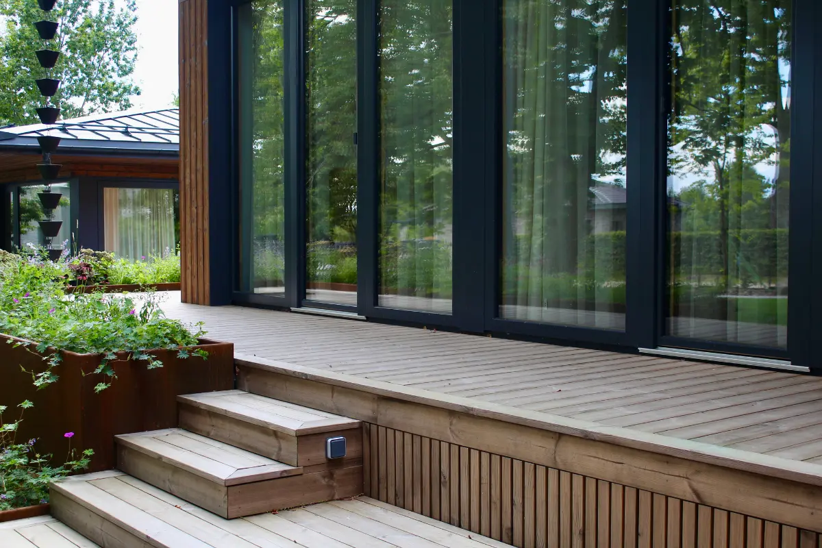 Termo pušies terasos grindys ir karkasas prie modernaus stiklo fasado – ilgaamžis ESSPO Wood sprendimas.
